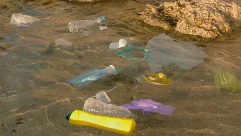 Disposable face masks and plastic debris on the water in surf zone. Stock Footage 143476141