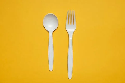 Disposable fork and spoon of corn starch on a yellow background. Stock Photos