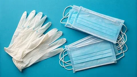 Disposable gloves and stack of medical masks made of non-woven material Stock Photos