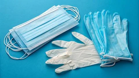 Disposable gloves and stack of medical masks made of non-woven material Stock Photos