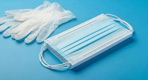 Disposable gloves and stack of medical masks made of non-woven material Stock Photos