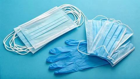 Disposable gloves and stack of medical masks made of non-woven material Stock Photos