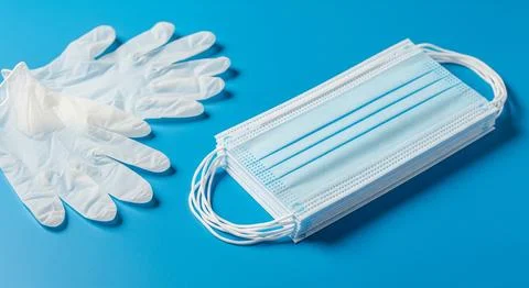 Disposable gloves and stack of medical masks made of non-woven material Stock Photos