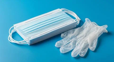 Disposable gloves and stack of medical masks made of non-woven material Stock Photos