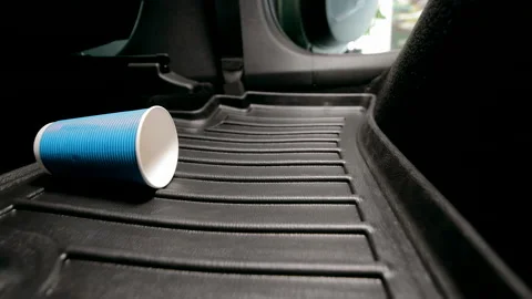 A disposable paper cup falls on the car floor mat in the car. Video stock 219625976