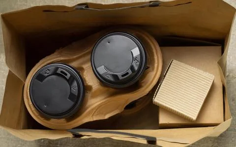 Disposable paper tableware. Coffee cups in holder, cookie carton and paper ba Stock Photos