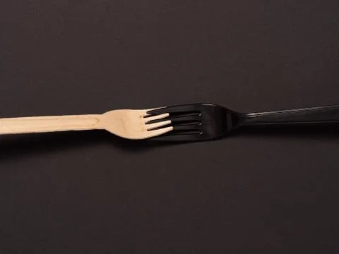 Disposable plastic and eco fork on black background. non-plastic concept Stock Photos