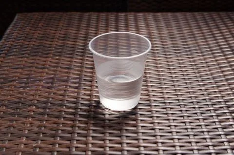 Disposable plastic cup half filled with water on the brown table Stock-Fotos