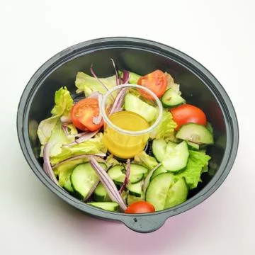 Disposable plastic plate with fresh vegetable salad on a white background Stock Photos