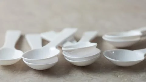 Disposable plastic spoons on marble background Stock Photos