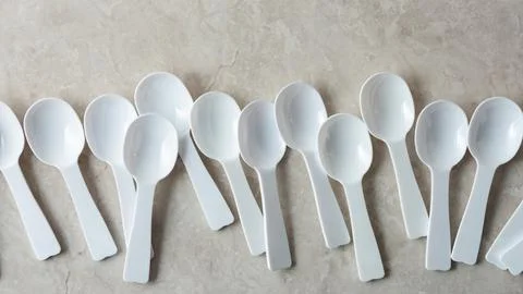Disposable plastic spoons on marble background Stock Photos