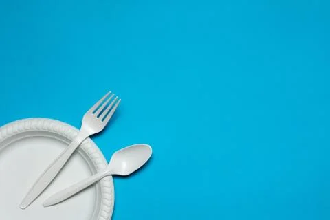 Disposable spoon, fork  and plate of corn starch on a blue background Stock Photos
