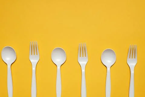 Disposable spoons and forks of corn starch on a yellow background Stock Photos