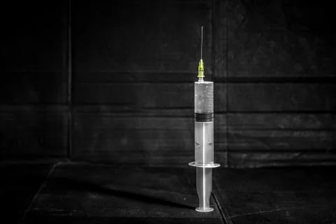 Disposable syringe on dirty dark background with dramatic light and shadow Stock Photos