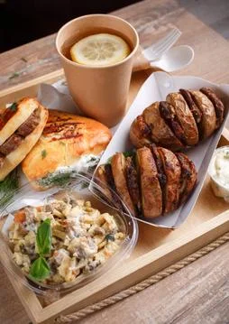 Disposable tableware, lemon tea, slate, mouth-watering sausage rolls and dill Stock Photos