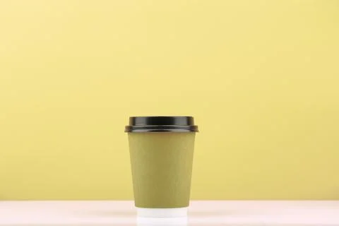 Disposable tea or coffee cup for hot drinks on white table against light khaki Stock Photos