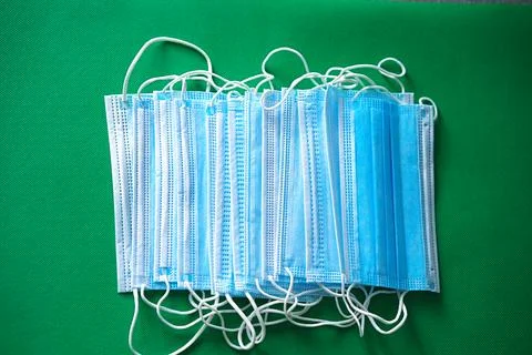 Disposable three-layer protective masks on a green background Stock Photos