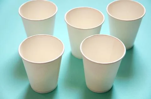 Disposable white kraft paper cups stand on blue background Stock Photos