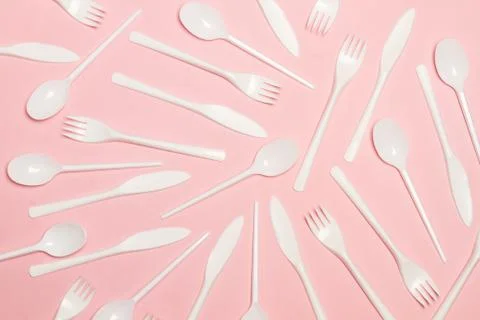 Disposable white plastic flatware on a pink background Foto stock