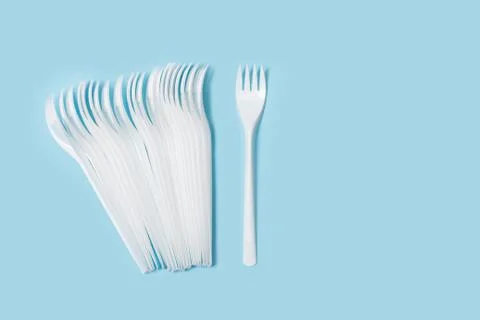 Disposable white plastic forks on a light blue background in a top view Stock Photos