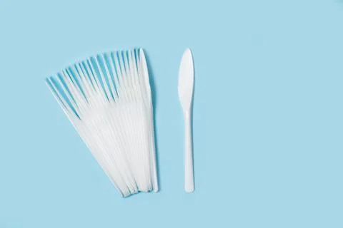 Disposable white plastic knifes on a light blue background Stock Photos