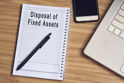 Disposal of fixed assets label on notepad with laptop and smartphone Foto stock
