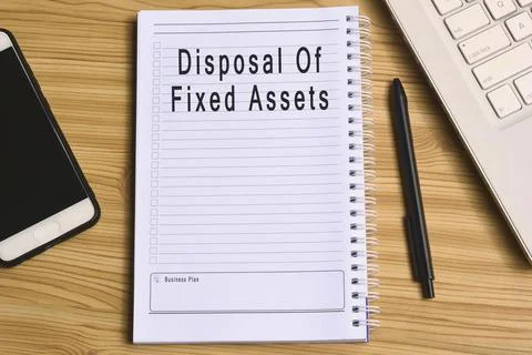 Disposal of fixed assets label on notepad with laptop and smartphone Stock Photos