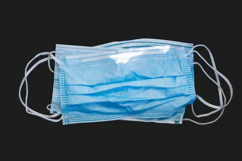 Disposed plastic protective face mask, on a dark background. Foto stock