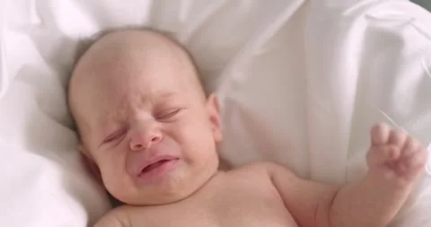 Dissatisfied, crying, upset, sad Newborn baby boy lying in nursery in crib with Stock-Footage 248628660