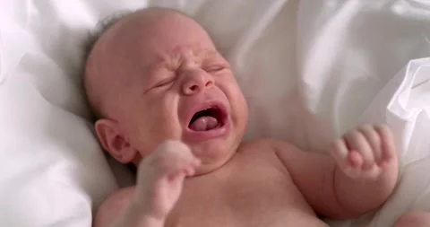 Dissatisfied, crying, upset, sad Newborn baby boy lying in nursery in crib with Stock-Footage 248629178