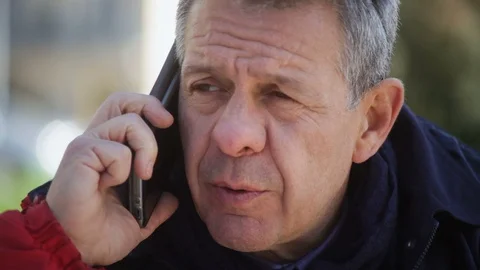 Dissatisfied Mature man in a red jacket talking on the phone Stock-Footage 100955839