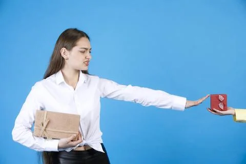 Dissatisfied nice female refusing from small gift, given by crop hand, while Stock Photos