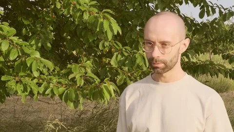 Dissatisfied young man 30-35 years old in glasses against backdrop of natur.. Video stock 244750194