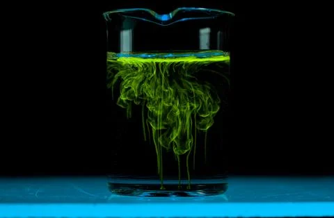Dissolution and spread of a yellow substance in a flask with a clear liquid. Stock Photos