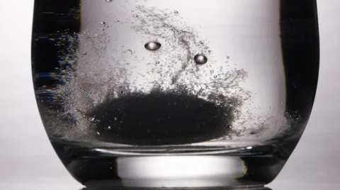 Dissolving tablet dropped into a glass of water, in slow motion Video stock 57484283
