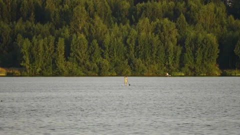 In the distance, a guy with a paddle on a board is floating on the lake Stock Footage 204960510