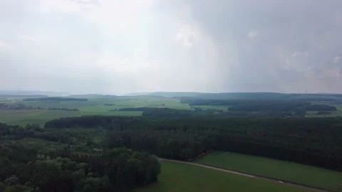 In the distance it is raining, a field, a forest and a road. Stock Footage 155598501
