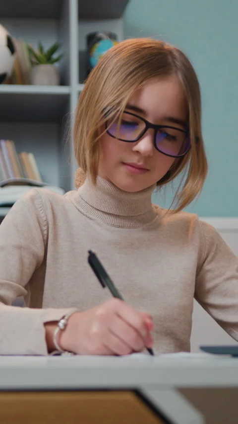 Distance learning. Focused caucasian pretty schoolgirl doing her homework at hom Stock Footage 330196178