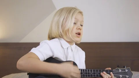 Distance learning online education. A cute kid boy learning to play the ukulele Stock Footage 129556074