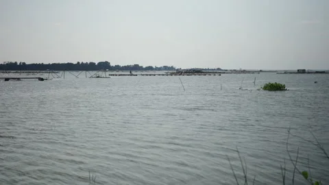 In the distance a man spreads the nets in the fish farm in the center of tri an Video stock 278766449