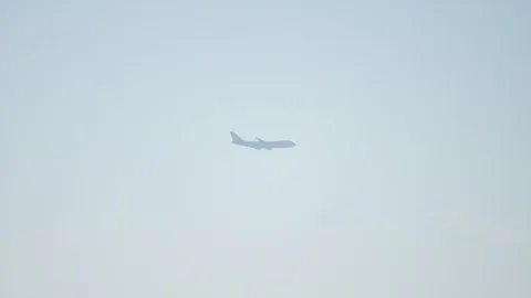 Distant 747 jumbojet airplane flying past a wind turbine 스톡 동영상 129641684