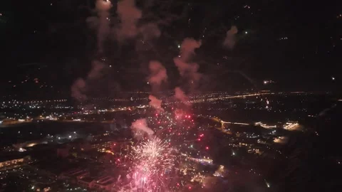 Distant Aerial Shot of Smoke and Subtle Firework Sparks Over a Coastal City at Video stock 334801258