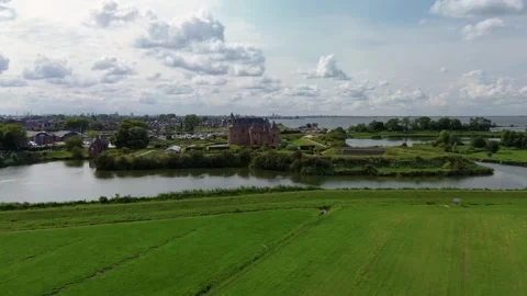 A distant aerial view of a medieval castle surrounded by water, lush green Stock Footage 314733037