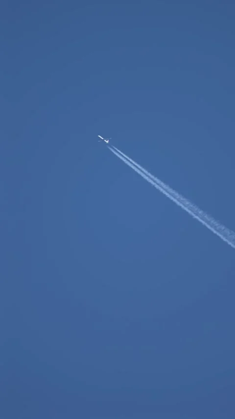 Distant aircraft creating narrow contrail line across open blue background Stock Footage 339281182