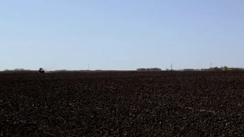 Distant alone tractor tills arable field at sowing campaign Video stock 280159973