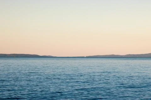 Distant blue adriatic sea with a tiny ferry ship far, outlines of islands mee Stock Photos