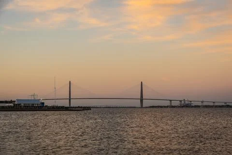 A distant bridge over a large body of water at sunset with Stock Photos