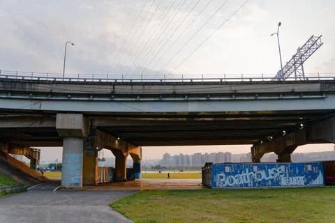Distant Bridge Standing Over River Levee at Riverside Park During Dusk 스톡 사진