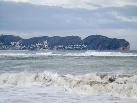 Distant cape merges with open ocean, Foamy surf under shifting cloud cover .. Photos