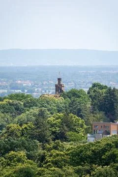 Distant Castle Tower Rising Above Lush Forest With Town and Hills in the Ba.. Stock Photos